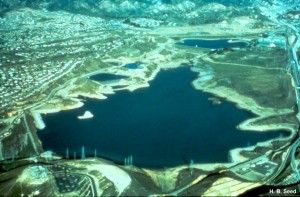 The dam is located in the lower left corner of this areal view. About 80,000 people living in the area downstream were threatened by the failure of the embankment and the very real possibility that the dam would fail completely, inundating the area by a catastrophic flood wave. Disaster was narrowly averted by drawing down the reservoir before the remaining remnant of the crest gave way.
