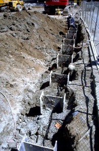 Steel H-piles were set in columns of soil-cement constructed by deep soil mixing. The soil-cement acts as a lagging that spans between the H-piles, and retains the soil during the eventual excavation.