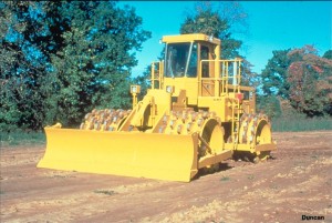 This photo shows a tamping-foot roller compacting clay. Like a padded drum roller or a sheepsfoot roller, the feet protruding from the drums penetrate into the fill when it is loose, compacting the fill from the bottom up. (Photo by Caterpillar).