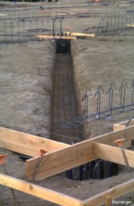 This trench extends diagonally from a corner column to an interior column location. The reinforcing steel cages will be lowered inside the trenches and supported on small concrete blocks.