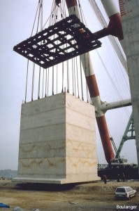 An offshore barge is used to lift each segment. The lifting cables pass through the guide-template so that the cables can act vertically (i.e., no inclination) on the quay wall segment.
