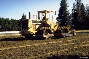 This cat is equipped with a blade for shaping the roadway and sheepsfoot rollers for compacting the clayey soils. Fill materials were brought to the site by trucks that spread the materials out in roughly 6 to 8 inch thick layers. The cat spread the material out evenly and compacted it at the same time.