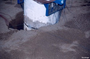 A gap has formed between the pile and soil at this stage of the test. When the pile loading direction is reversed, the pile will move through the gap with little resistance until it develops contact with the soil again. This feature of behavior is important to understanding seismic response of pile foundations. Also notice the instrumentation for measuring pile displacements, strains, and curvatures. 